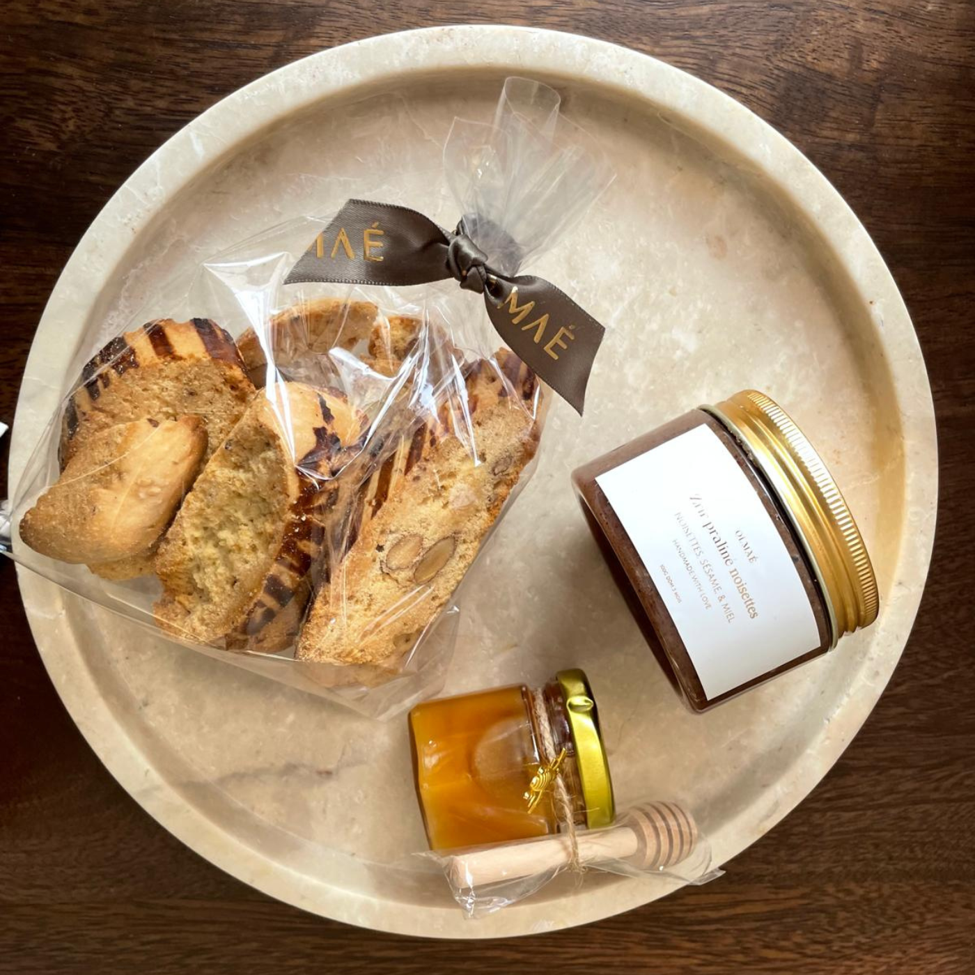 Fabrication artisanale Olmaé : sélection de matières naturelles et savoir-faire français.  Pâte de praliné, croquants aux amandes et mini pot de miel.